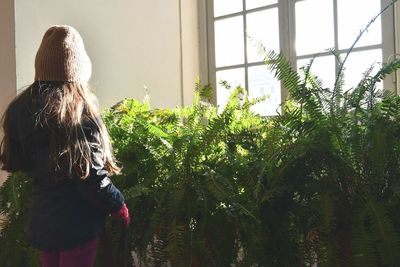 Rear view of girl standing against trees