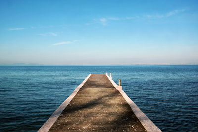 Pier over sea against blue sky