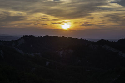 Scenic view of silhouette mountains against orange sky