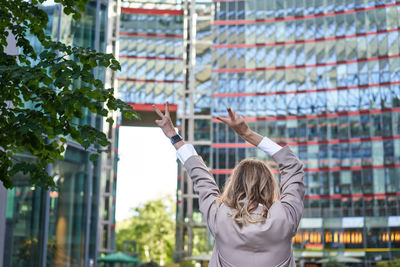 Young woman with arms outstretched standing in city