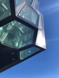 Low angle view of glass building against blue sky