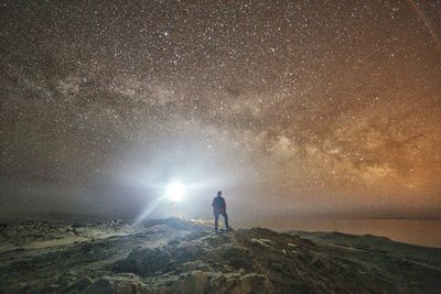 Rear view of woman standing against sky at night