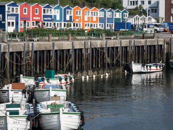 Sailboats moored on harbor by buildings in city