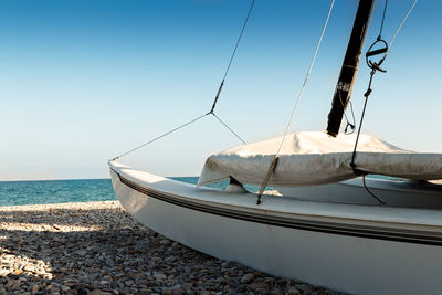 Sailboat moored on beach against clear sky