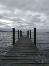 Wooden pier over sea against sky