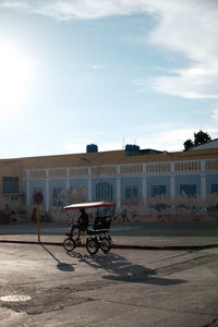 Man riding bicycle on road by buildings