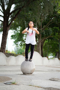Full length of cute girl standing on sphere at park