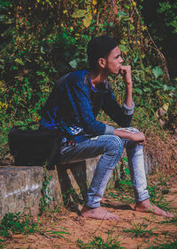 Young man looking away while sitting on bench