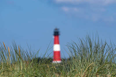 Lighthouse on field against sky