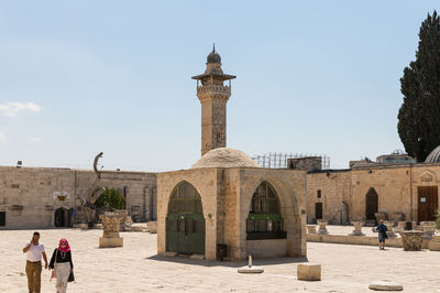 People in front of historical building against sky