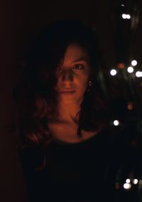 Close-up of young woman standing outdoors at night