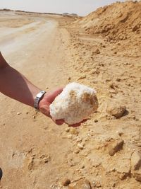 Midsection of man holding sand at beach