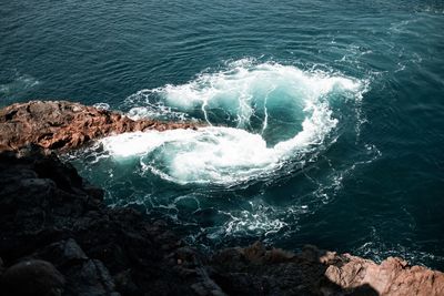 High angle view of waves splashing on rocks