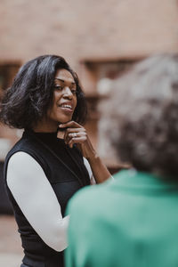 Businesswoman with hand on chin talking with female colleague in office