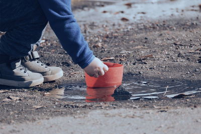 Low section of child holding container on puddle