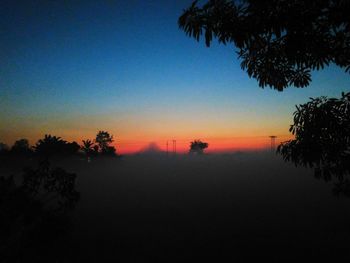 Scenic view of silhouette trees against clear sky at sunset