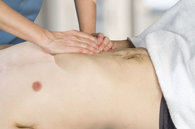 Midsection of woman massage therapist analyzing man in beauty spa
