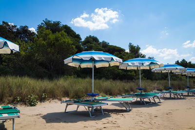 Deck chairs on beach against sky