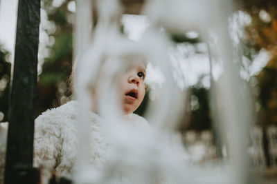 Low angle view of cute girl seen through metal