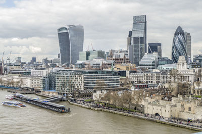 Modern buildings by river against sky in city