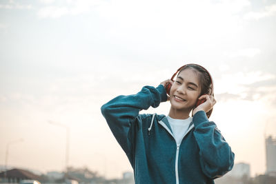 Portrait of smiling young woman against sky