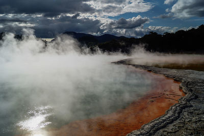 Scenic view of hot spring against cloudy sky