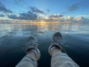 Feet of baby by sea against sky during sunset