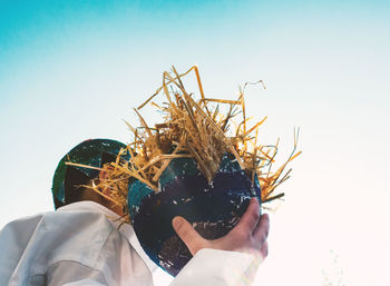 Low angle view of man holding easter eggs against clear sky