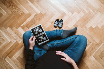 Woman holding photograph while sitting on hardwood floor