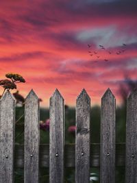 Close-up of wooden fence against cloudy sky during sunset