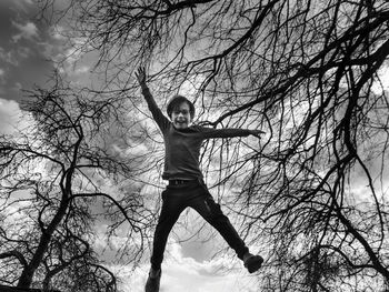 Portrait of boy jumping on bare tree