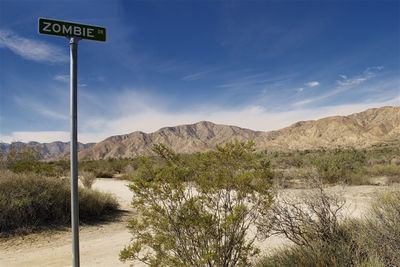 Road sign by mountains against sky