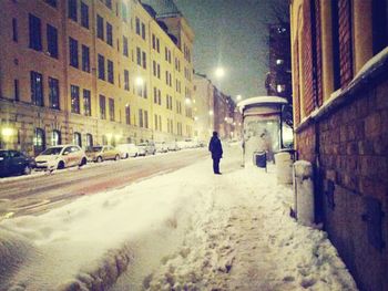 Woman walking in illuminated city at night