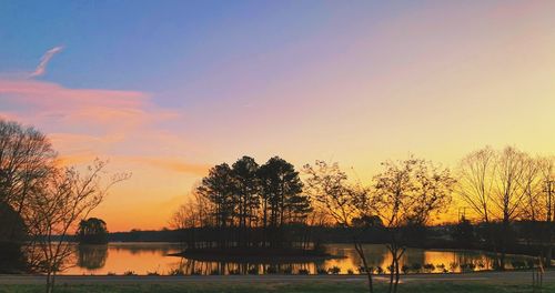 Silhouette trees by lake against sky during sunset