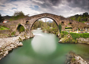 Arch bridge over river against sky