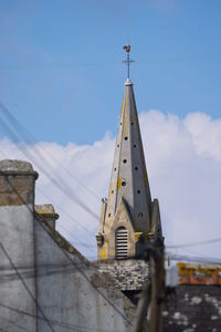 Low angle view of cross amidst buildings against sky