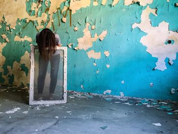 Woman bending against weathered wall in abandoned room