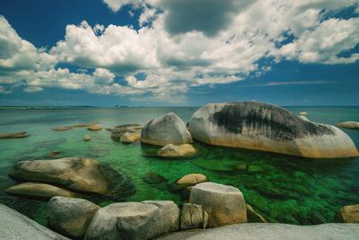 Rocks on sea shore against sky