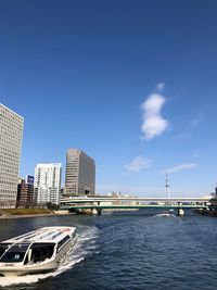 Bridge over sea by buildings against sky in city