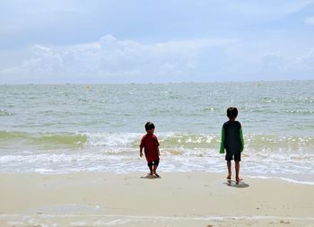 Rear view of woman walking at beach against sky