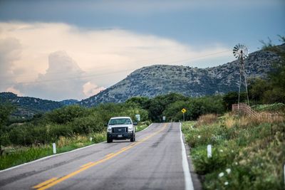 Car on road by mountains against sky