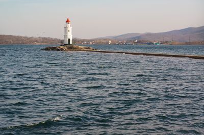 Lighthouse by sea against sky