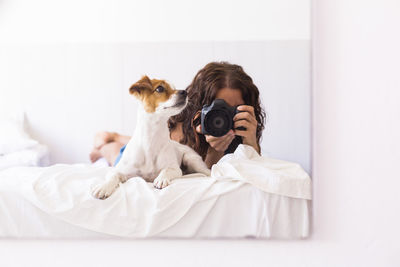 Reflection of woman photographing by dog in mirror at home