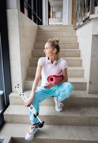 Full length of young woman sitting on staircase