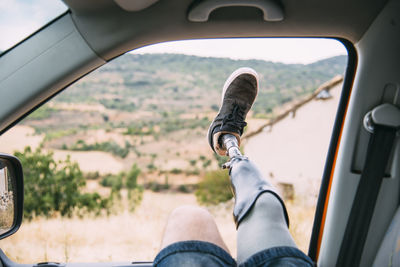 Legs of prosthetic young man dangling out of camper van window