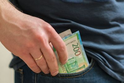 Midsection of man removing paper currencies from pocket