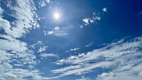 Low angle view of sunlight streaming through clouds