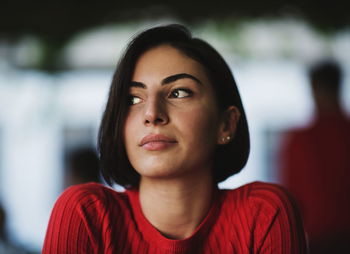 Young woman looking away while sitting indoors