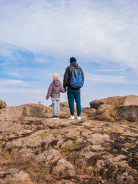 Travelers father daughter walking climbing mountain summit enjoying aerial view cloudy sky together