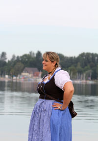 Young woman in dirndl standing at lakeshore